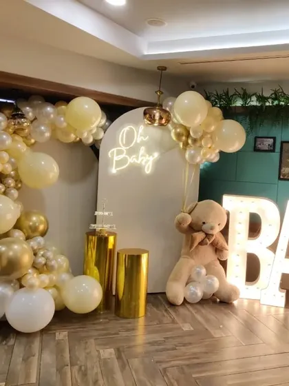 Here is the complete 'Oh Baby' shower setup with the marquee letters included. The combination of the balloon arch, neon sign, teddy bear, and illuminated letters makes for a full and festive display.