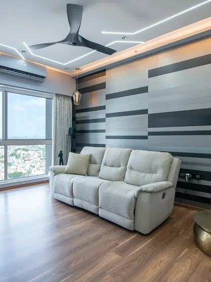 A sophisticated living space at SNN Clermont with a gradient-striped feature wall that adds depth and movement. The plush recliner sofa is designed for ultimate comfort.