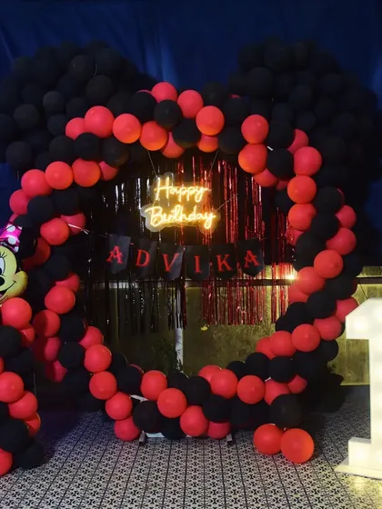 A fun Minnie Mouse themed first birthday party. I created a custom heart-shaped balloon arch using red and black balloons, with a Minnie Mouse foil balloon, a neon sign, and a light-up number '1'.