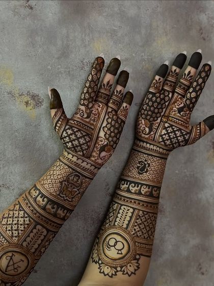 This design showcases a mix of symbolic elements for an engagement, including initials, rings, and auspicious elephants. The patterns are dense on the forearm and transition to more open work on the palm.