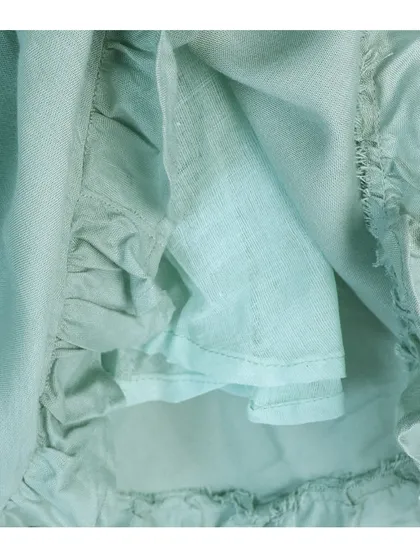 A close-up of the inner lining and ruffled hem of a child's frock, showing fabric quality and stitching detail.