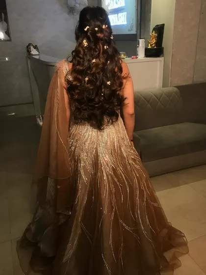 Here is the back view of the hairstyle from the previous image. The soft curls and scattered flowers create a beautiful, ethereal look that is perfect for a romantic evening function.