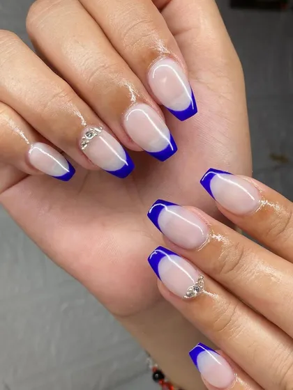 A bold and beautiful set of coffin-shaped nails with a royal blue French tip and silver rhinestone accents.