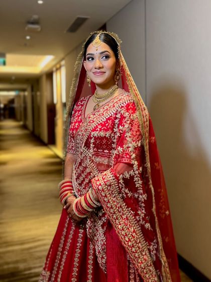A classic pose in a hotel corridor, which creates a beautiful, dramatic effect. Her red lehenga stands out beautifully.