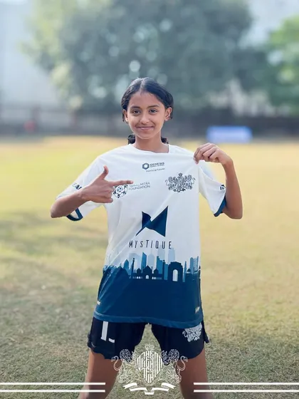Proudly representing the team. A player points to the crest on her jersey, a symbol of our collective identity.