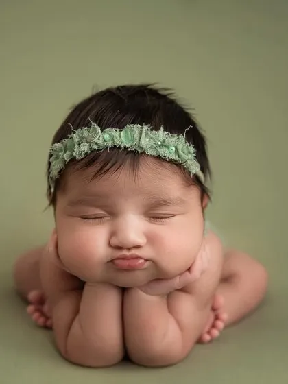 A perfect 'chin on hands' pose with the most adorable pouty lips. The sage green background is a beautiful, gender neutral color option.