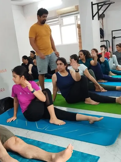 An instructor observes the class during a seated spinal twist, ensuring everyone maintains safe and effective alignment.