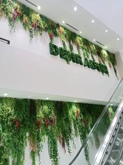 This project showcases our ability to handle large-scale, custom branding installations. We created a multi-story artificial plant wall that flows down two levels, with the brand name "Dehradun" seamlessly integrated using foliage for a memorable visual statement.