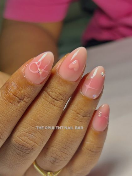 A close-up of these dreamy baby pink nails. The combination of 3D hearts, bows, and tiny rhinestones is just perfect.