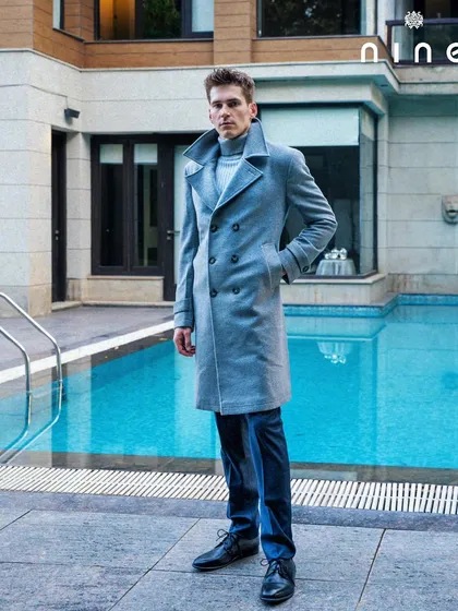 The grey double-breasted overcoat, styled for a classic winter look by the poolside.