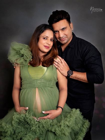 This portrait beautifully showcases the baby bump. The sheer fabric of the green gown and the couple's loving embrace create a stunning and artistic image celebrating the female form during pregnancy.