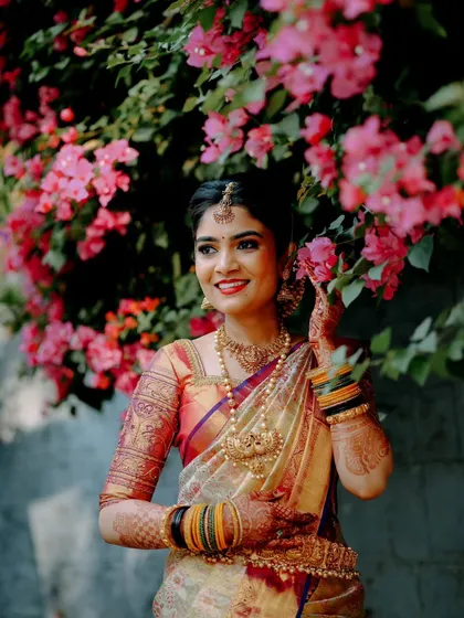 A bridal portrait should be more than just a photo; it should capture her radiance. By using the vibrant bougainvillea as a natural frame, this shot highlights the bride's elegance and the rich colors of her wedding saree.