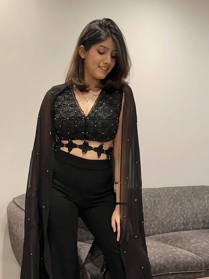 A chic and modern party look. This black co-ord set features a detailed crop top with a dramatic cape, perfect for making a statement at any evening event.
