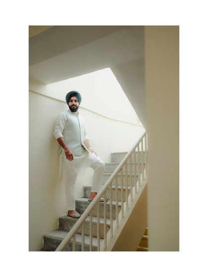 A full-length portrait of the groom in his elegant white and blue attire, showcasing his style on his wedding day.