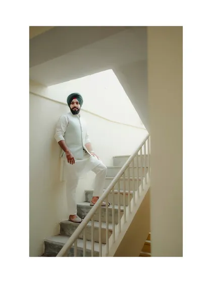 A full-length portrait of the groom in his elegant white and blue attire, showcasing his style on his wedding day.