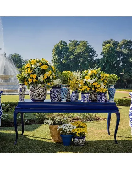 A beautiful console table decorated with blue pottery vases and bright yellow flowers, set against a garden backdrop. A perfect fusion of elegance and nature.