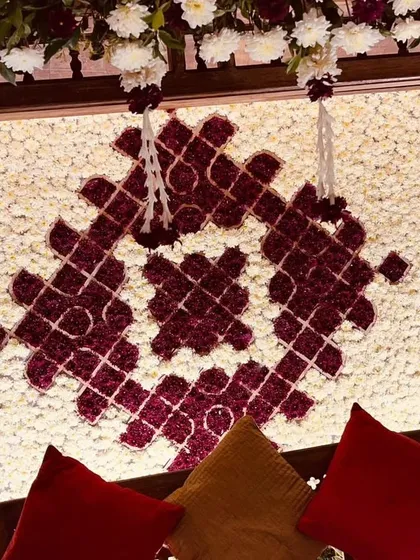A detailed look at the intricate floral pattern created on the backdrop for our jhoola setup. We used deep red and white flowers to create a beautiful motif against a wall of white blooms.
