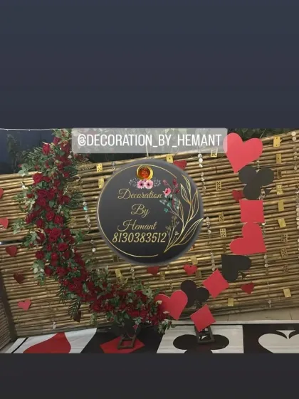 A creative wall decoration for a play card themed party. A bamboo panel is decorated with a cascade of red roses and a garland of red and black paper hearts, tying into the theme.