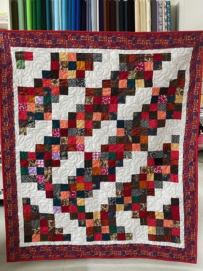 A scrappy quilt made from many different fabrics, arranged in a "trip around the world" pattern.