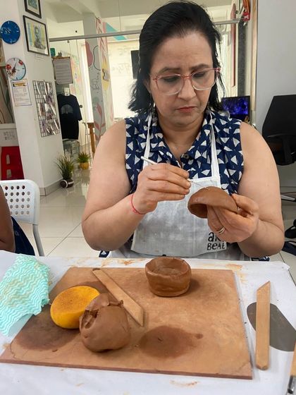 A participant carefully shapes a small bowl from clay. The process of handbuilding is slow, mindful, and deeply satisfying.