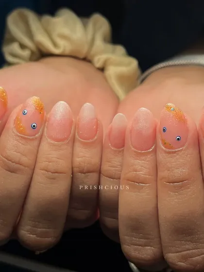No nazar with these cute evil eye nails. This design features tiny, hand-painted evil eyes on a sparkly orange glitter tip.