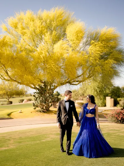 For their reception, we styled Aditi in a stunning electric blue lehenga and Diego in a classic black tuxedo. The bold color of her outfit looks incredible against the lush green landscape.