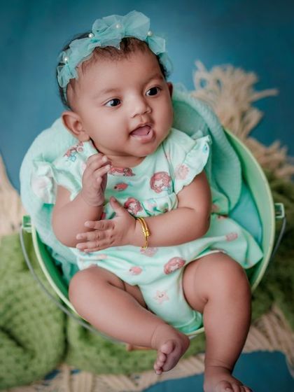 A curious little mermaid. This baby is wide awake and taking in the world from her cozy bucket, dressed in a sweet aqua-colored outfit.
