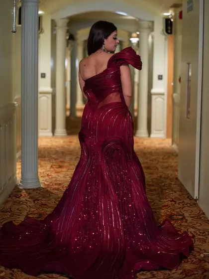 The back view of our surreal red sculpted gown. The intricate, textured design flows down the length of the dress and into a dramatic train, creating a stunning and artistic silhouette.