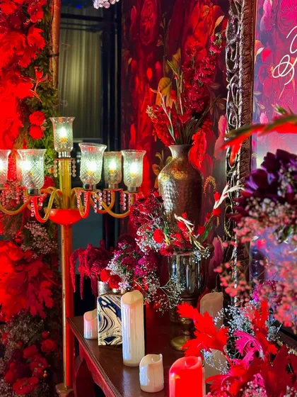 A detailed corner vignette featuring a tall candelabra, hammered gold vases, and an abundance of red flowers. These carefully styled corners added depth and richness to the overall decor of the banquet hall.