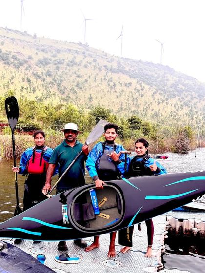 The team poses with their coach and a state-of-the-art racing kayak. We provide our athletes with top-tier equipment and expert coaching.