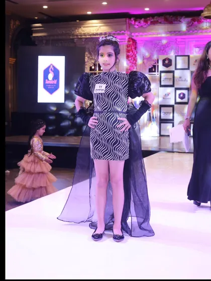 A full-length view of one of our young models presenting her outfit on the grand finale stage. We ensure every participant gets their moment in the spotlight.