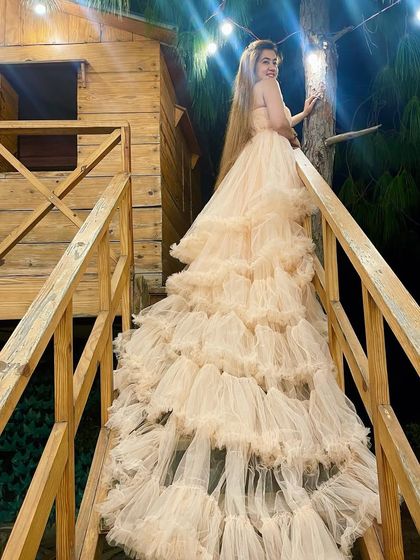 Make your own magic with this champagne-colored ruffle trail gown. The long, cascading train of layered tulle looks ethereal and romantic, perfect for a photoshoot at a rustic location like this treehouse.