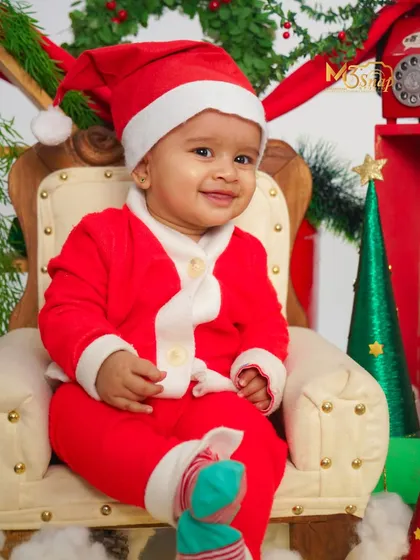 The perfect little Santa. This Christmas-themed shoot features a baby in a Santa suit, sitting in a miniature armchair. It's a festive way to celebrate their first Christmas.
