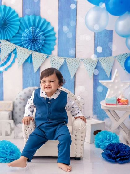 A big, cheesy grin from the birthday boy, clearly enjoying his special day in our blue-themed studio setup.