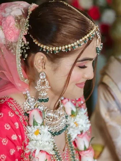 A side profile of our beautiful bride, showcasing her intricate mathapatti and heavy earrings. This highlights how we help style every element, from the main necklace to the smallest accessory.