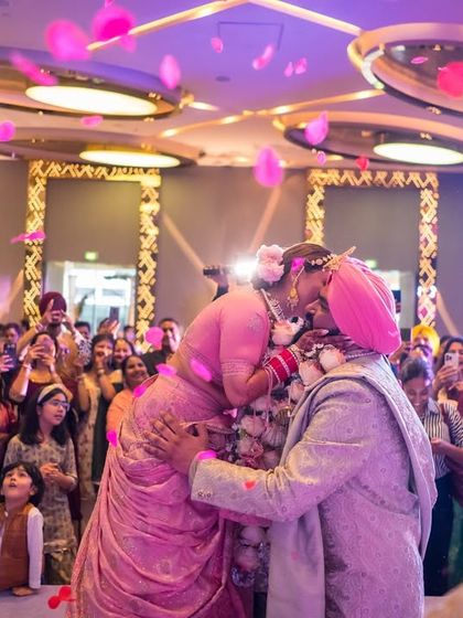 A beautiful moment of a Sikh couple during their Anand Karaj ceremony, surrounded by family as petals rain down.