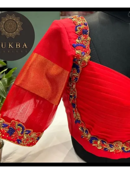 A side view of the red blouse, detailing the sweetheart neckline, ruched front, and embroidered sleeve.