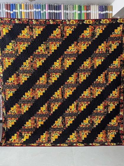 A beautiful Log Cabin quilt with a sunflower theme, arranged in diagonal stripes.
