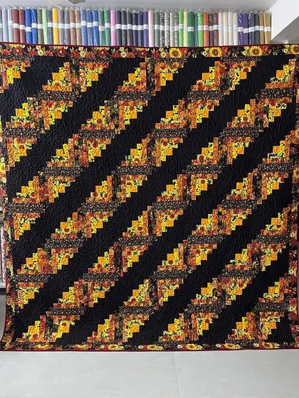 A beautiful Log Cabin quilt with a sunflower theme, arranged in diagonal stripes.