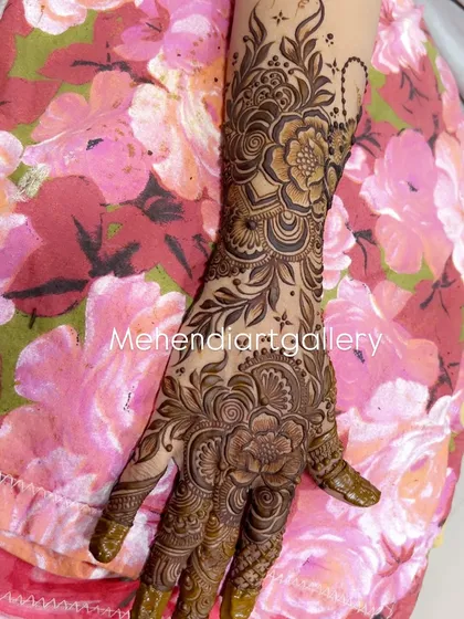 This full-hand design showcases a dense floral pattern with intricate shading. The art covers the entire hand and extends up the arm, creating a breathtaking look for any bride.