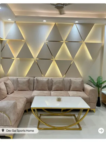 This living room features a stunning accent wall with backlit triangular panels. The neutral sofa and gold-framed coffee table complete this ultra-modern and luxurious look.