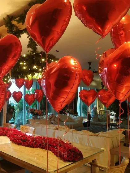 Another view of the romantic Valentine's setup, with a long table runner of red roses and heart balloons floating above.