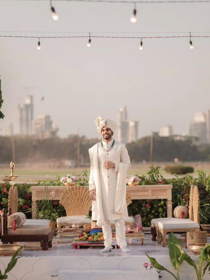 The groom stands proudly on the mandap, with the Mumbai city skyline creating a modern and unique backdrop for this wedding portrait.