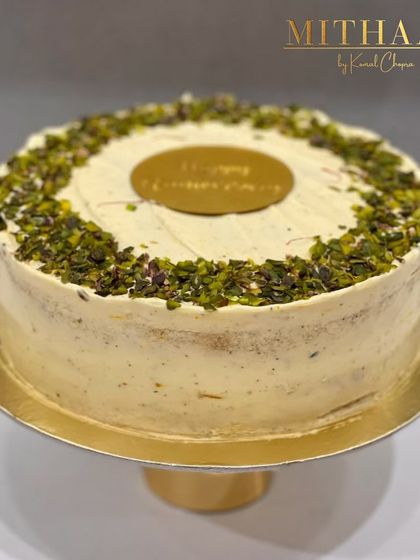 This anniversary cake is a celebration of nutty, subtle flavors. A ring of crushed pistachios crowns the top, with a simple "Happy Anniversary" plaque at the center for a touch of elegance.