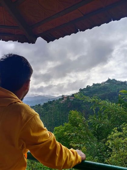 A traveler enjoying the serene view from a balcony in Coorg. Our chosen stays always offer a connection to the beautiful surroundings.