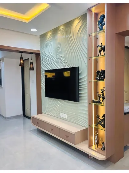 For clients who want a true statement piece, I design unique TV walls like this one. This unit features a custom 3D textured panel that creates a wave-like pattern, beautifully highlighted by integrated lighting. It’s paired with a floating console and a backlit glass display cabinet for a truly artistic touch.