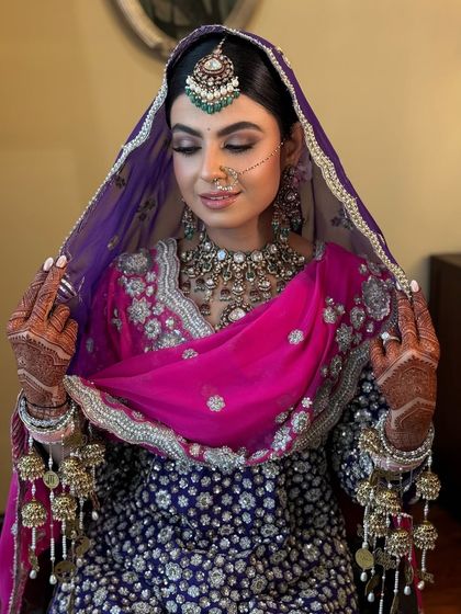 The bride adjusting her dupatta, giving a glimpse of her traditional hairstyle.