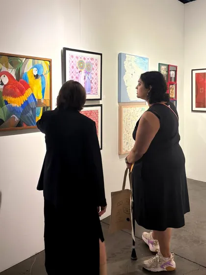 Visitors admiring a colorful painting by Senaka Senanayake at our Seattle Art Fair booth.