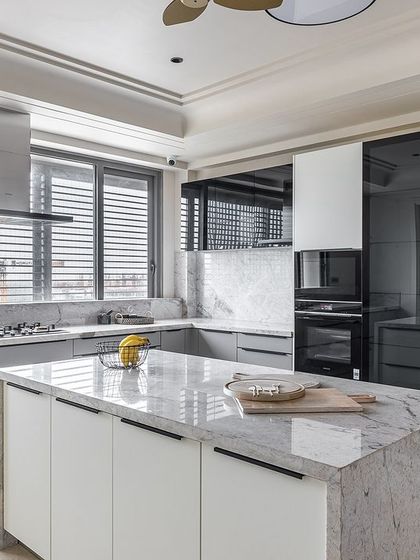 Longline handles in black create a striking graphic contrast against the light-colored cabinetry, emphasizing the kitchen's clean, horizontal lines.