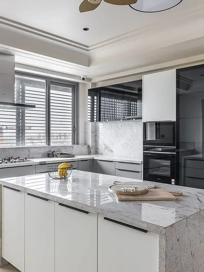 Longline handles in black create a striking graphic contrast against the light-colored cabinetry, emphasizing the kitchen's clean, horizontal lines.